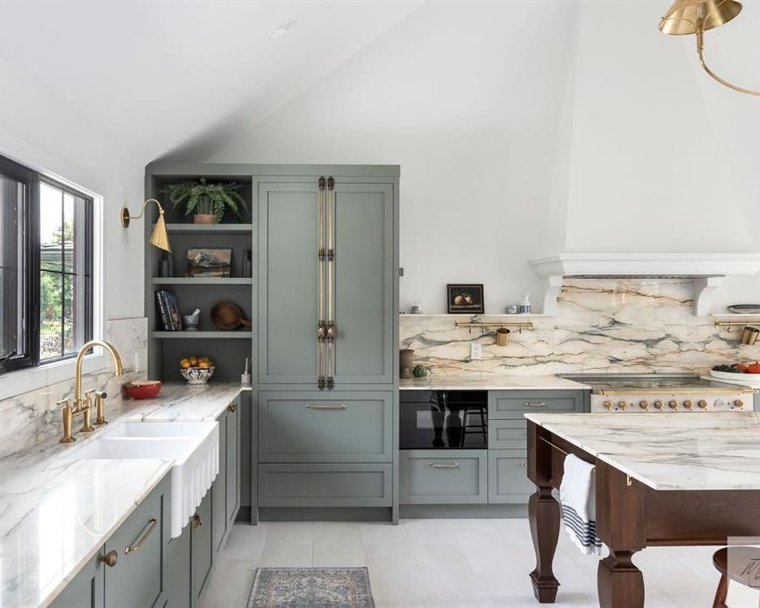 Custom sage-green kitchen with an arched range hood and marble surfaces